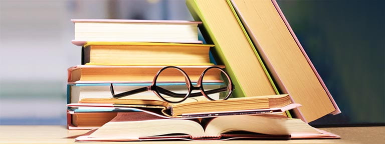 A stack of books with a pair of glasses resting on them